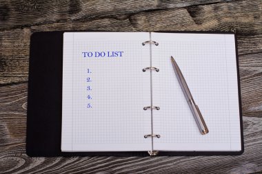 Yapılacaklar listesi not etmek üstünde ahşap zemin, iş kavramı üzerine metal kalem ile yazılı