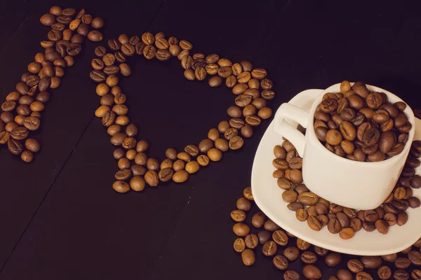 Pequeña taza blanca con granos de café sobre un fondo de madera oscura. Me encanta la composición del café — Foto de Stock