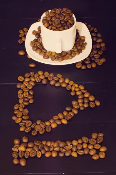 Pequeña taza blanca con granos de café sobre un fondo de madera oscura. Me encanta la composición del café — Foto de Stock