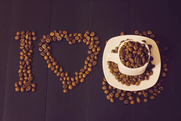 Pequeña taza blanca con granos de café sobre un fondo de madera oscura. Me encanta la composición del café — Foto de Stock