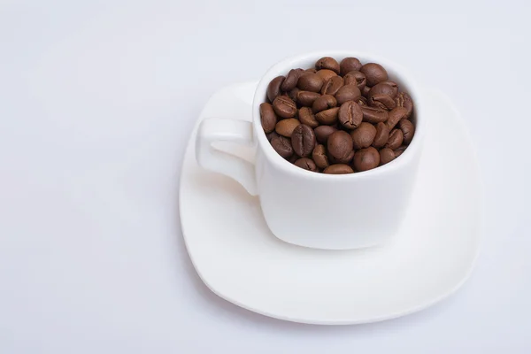 Small white cup with coffee beans on a white background. Isolated — Stock Photo, Image