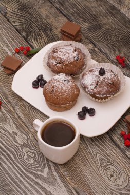 cupcake fincan kahve, ahşap arka plan beyaz küçük beyaz bir tabakta çilek ile