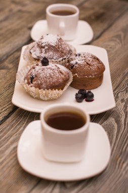 cupcake fincan kahve, ahşap arka plan beyaz küçük beyaz bir tabakta çilek ile