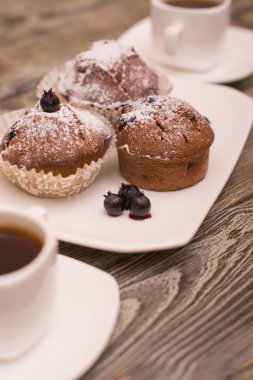 cupcake fincan kahve, ahşap arka plan beyaz küçük beyaz bir tabakta çilek ile