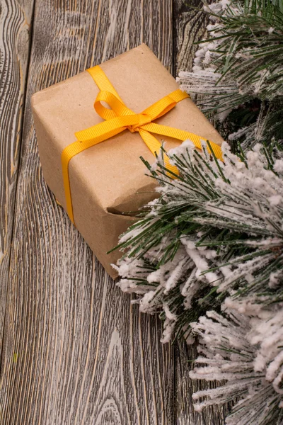 Gift box, fir branch in snow on wooden background — Stock Photo, Image
