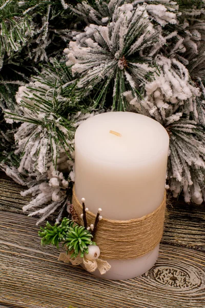 Fir branch in snow, Christmas decorations, candle on wooden background — Stock Photo, Image