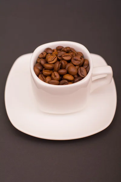 Karanlık bir arka plan üzerinde beyaz bir fincan kahve çekirdekleri — Stok fotoğraf
