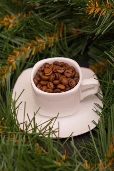 Chicchi di caffè in una tazza bianca e un ramo di abete — Foto Stock