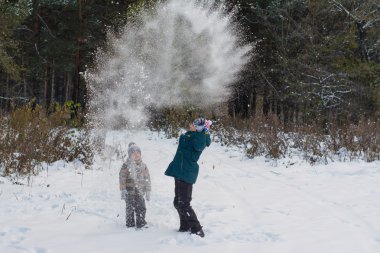 İki erkek ile kış çam ormanı karda oynarken