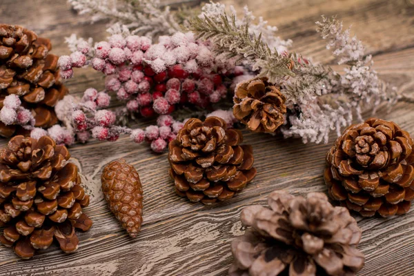 Fir branch in snow, cone on wooden background