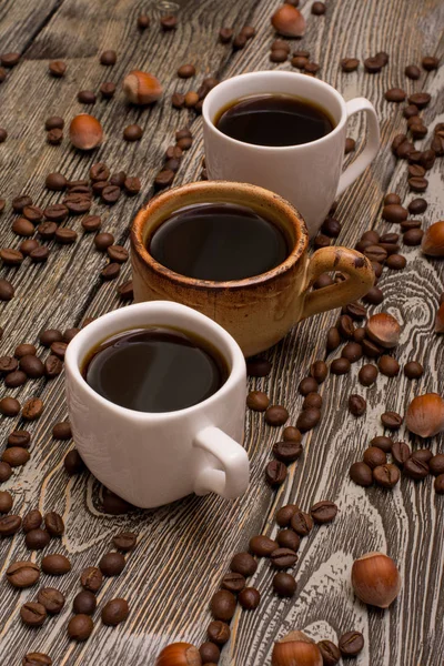 Három csésze kávé-, mogyoró- és fa háttér kakaóbab — Stock Fotó