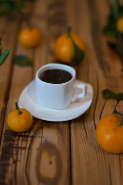 Küçük beyaz fincan kahve ve ahşap zemin üzerine mandalina