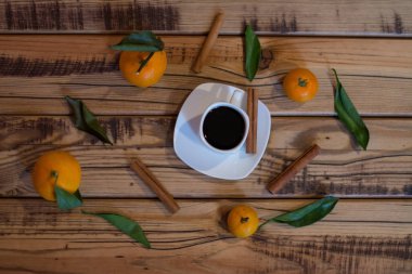 Küçük beyaz fincan kahve, tarçın ve ahşap zemin üzerine mandalina