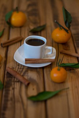 Küçük beyaz fincan kahve, tarçın ve ahşap zemin üzerine mandalina