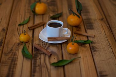 Küçük beyaz fincan kahve, tarçın ve ahşap zemin üzerine mandalina