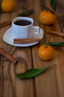 Küçük beyaz fincan kahve, tarçın ve ahşap zemin üzerine mandalina