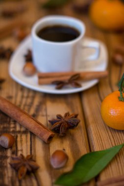 Küçük beyaz fincan kahve, tarçın, yıldız anason, fındık ve ahşap zemin üzerine mandalina