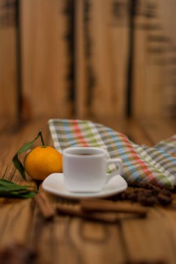 Küçük beyaz fincan kahve, tarçın, yıldız anason ve mandarin ahşap arka plan üzerinde