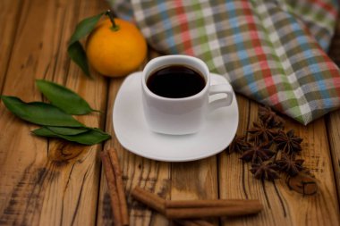 Küçük beyaz fincan kahve, tarçın, yıldız anason ve mandarin ahşap arka plan üzerinde
