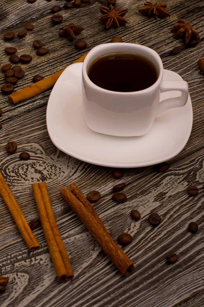 Pequeña taza de café blanco, palitos de canela, anís estrellado sobre fondo de madera — Foto de Stock