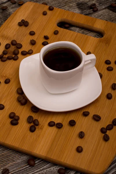 Liten kopp av kaffe, rostade kaffebönor på trä bakgrund — Stockfoto