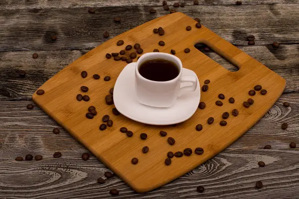 Malý šálek kávy, pražené kávové boby na dřevěné pozadí — Stock fotografie