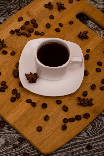 Piccola tazza di caffè bianco, anice stellato su sfondo di legno — Foto Stock