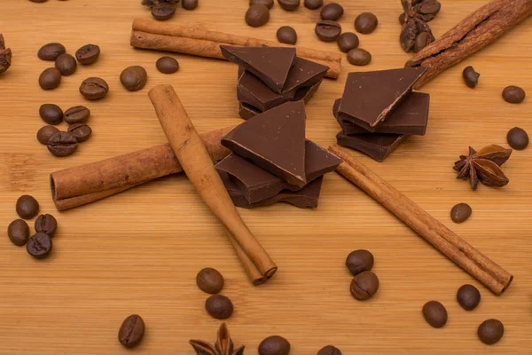 Chocolate, palitos de canela, granos de cacao, anís estrellado sobre fondo de madera — Foto de Stock