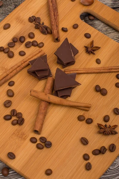 Schokolade, Zimtstangen, Kakaobohnen, Sternanis auf Holzgrund lizenzfreie Stockbilder
