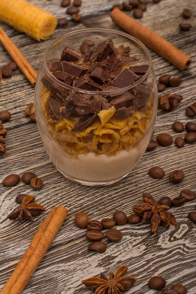 Dolci allo yogurt con cioccolato e biscotti, bastoncini di cannella, fave di cacao, anice stellato su fondo di legno — Foto Stock
