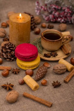 Fincan kahve, bademli kurabiye, kurabiye, ceviz, fındık, tarçın, yıldız anason, koni, mum, köknar dalı çul kumaş üzerine