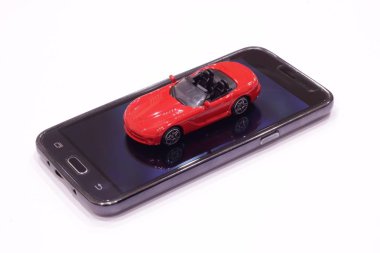  Kırmızı oyuncak araba ve siyah bir akıllı telefon