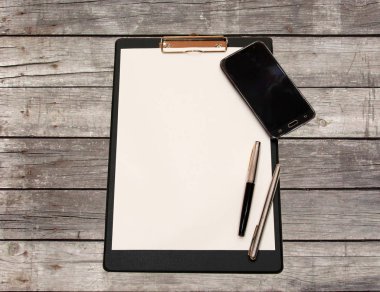 Bir kalem ve yönetim kurulu yapılmış ahşap bir masa üstünde smartphone ile beyaz kağıdın