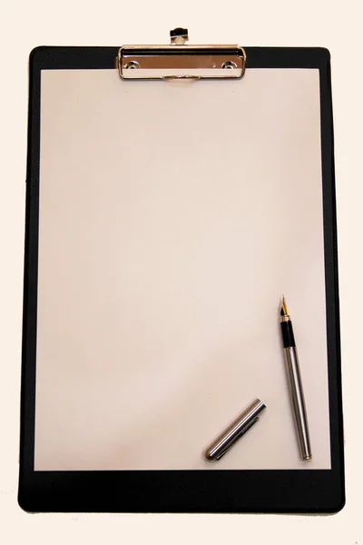 Ett vitt pappersark med en penna monterad på en mapp — Stockfoto