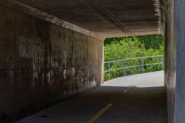 Yolun altındaki bisiklet yolu tüneli, keskin viraj ve korkuluk ötesi, yatay görünüm