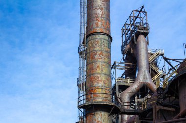 Paslı metal yapılardan oluşan labirent, eski terk edilmiş çelik fabrikası, geniş mavi gökyüzü kopya alanı, yatay görünüm