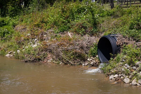 从黑色排水管进入溪流的水 径流环境污染 横向方面 — 图库照片