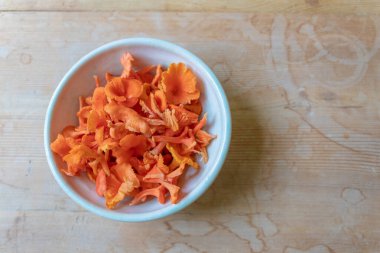 Bir kase parlak kırmızı ve turuncu tarçınlı mantar ezilmiş ahşap arka plan, kopyalama alanı, yatay görünüm