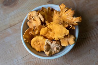 Yıpranmış ahşap bir masa üzerinde orta boy mantar kasesi, yatay görünüm.