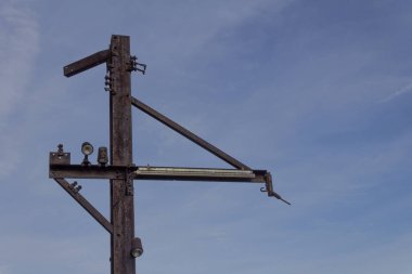 Mavi gökyüzüne karşı düz çelik direkler ve aydınlatma armatürleri, paslanmış metal parçacıklar, yatay görünüm