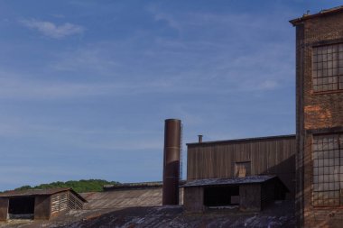 Mavi gökyüzüne karşı endüstriyel binaların şekilleri ve dokuları, yatay görünüm