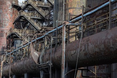 Paslı metal boruların, kaldırımların, kentsel endüstriyel mimarinin karmaşık arka planı, yatay görünüm