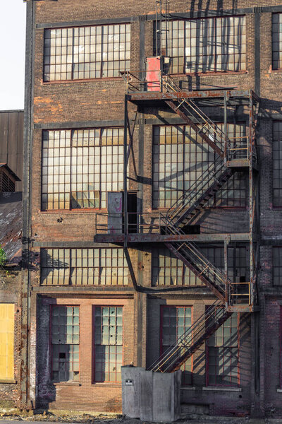 Exterior of an old warehouse building with brick, windows, fire escape, vertical aspect