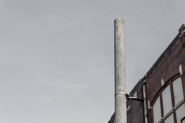 Single smokestack beside an old industrial building, copy space, horizontal aspect
