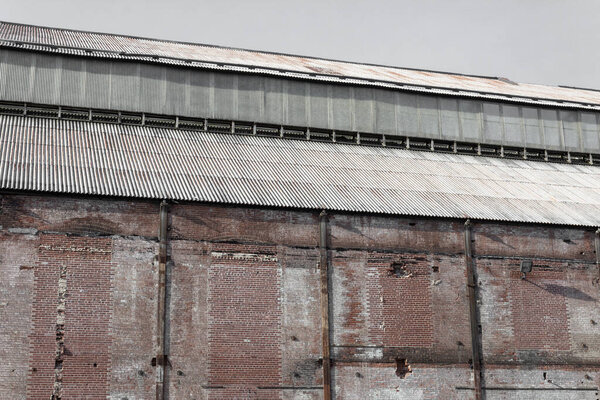 Weathered wall and steel roof of an old industrial warehouse, horizontal aspect