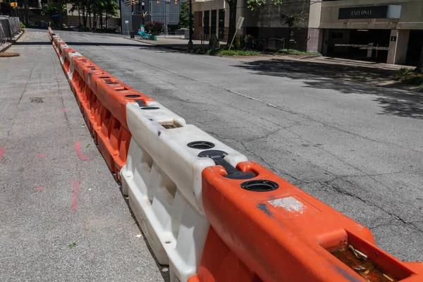 City street divided by orange and white hard plastic traffic barriers, urban construction site, horizontal aspect