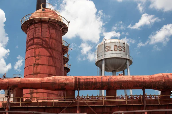 Sloss Furnaces Ulusal Tarihi Eserler, Birmingham Alabama USA, fırın ve su kulesinin geniş görüşü beyaz bulutlu parlak mavi gökyüzü, yatay görünümü