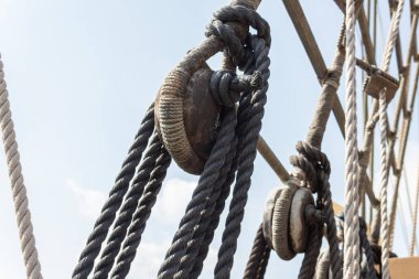 Closeup of block and tackle, wrapped rope and rigging detail on an old sailing ship, horizontal aspect clipart