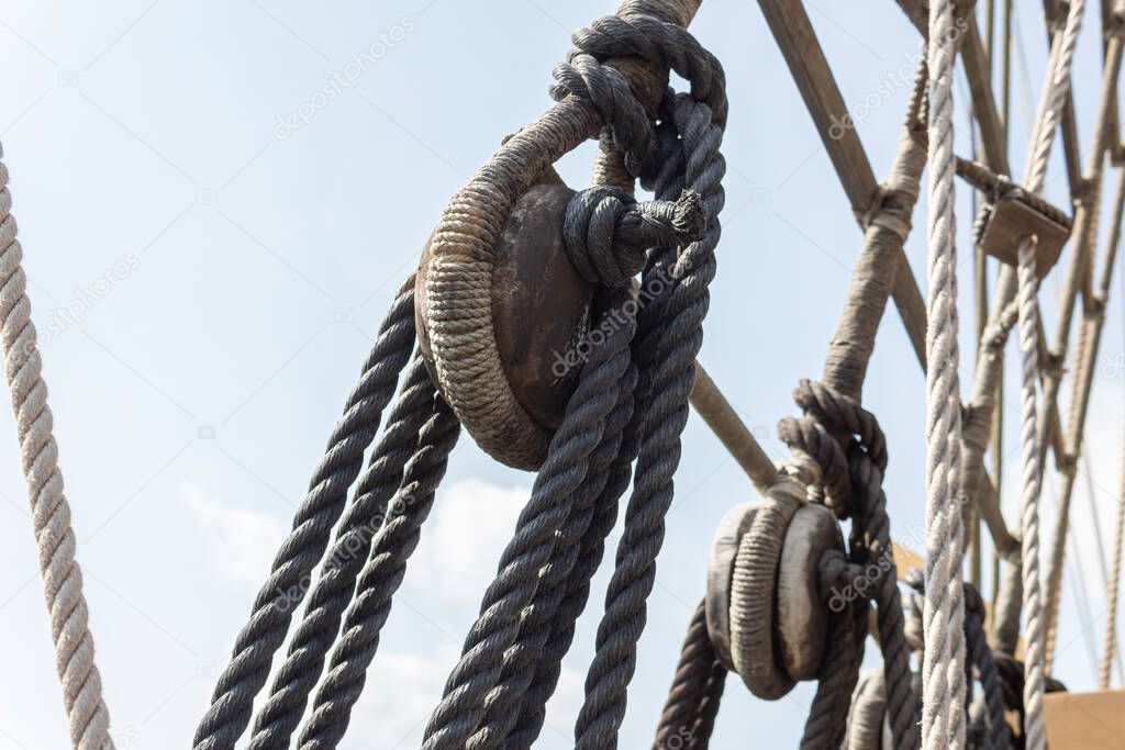 Closeup of block and tackle, wrapped rope and rigging detail on an old sailing ship, horizontal aspect