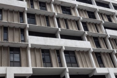Beton, koyu renkli pencereli, yatay görünümlü kentsel apartman